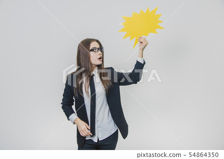 Young woman is holding a yellow speech bubble, which is star-shaped, isolated, on the white 54864350