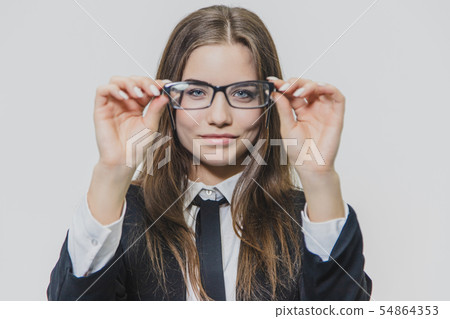 Beautiful businesswoman puts off herstylish glasses. Beautiful young woman is holding glasses with 54864353