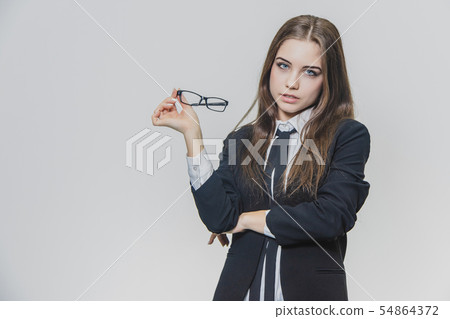 Beautiful businesswoman puts off herstylish glasses. Girl wears eyeglasses. Beautiful young woman is 54864372
