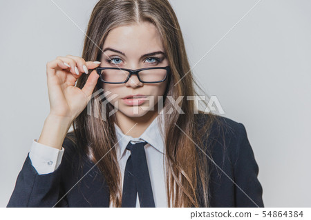 Close up portrait of a serious businesswoman, who is touching the black rim of glasses with one hand 54864384