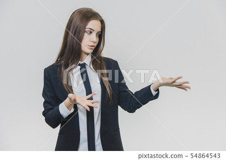 Serious thoughtful brown-haired businesswoman is thinking while showing something with her hands. 54864543