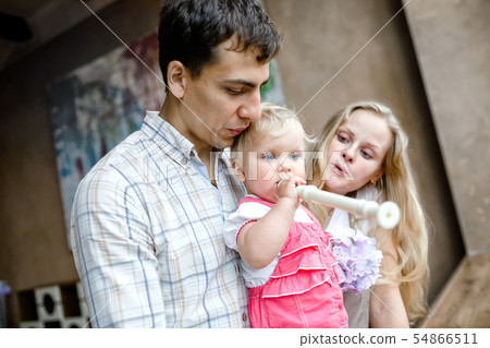 Tender family hugs. Mom, dad and daughter enjoy each other, girl playing a pipe 54866511