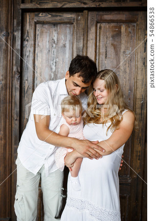 Family portrait. Happy couple holding a little girl. Awesome mom is pregnant 54866538