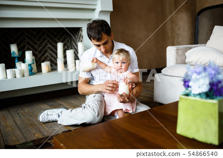 Portrait of happy father and daughter in rose dress at home, sitting on a floor 54866540