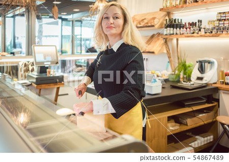 Shop clerk in deli cutting cheese 54867489