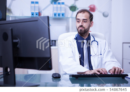 Portrait of doctor working on his computer in cabinet at the hospital 54867645