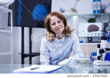 Portrait of successful scientist smiling to the camera in her laboratory office Portrait of successful scientist smiling to the camera in her laboratory office 54867669