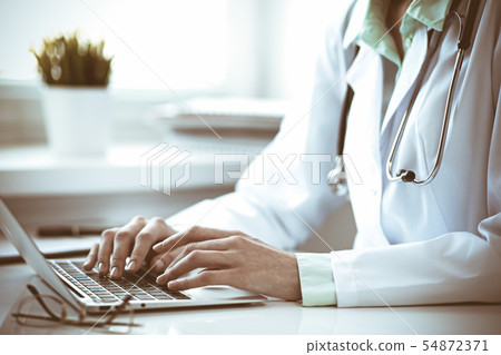 Doctor woman using laptop computer while sitting at the desk near window in hospital. Medicine and 54872371