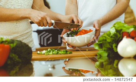 Closeup of human hands cooking in kitchen. Mother and daughter or two female friends cutting Closeup of human hands cooking in kitchen. Mother and daughter or two female friends cutting 54872547