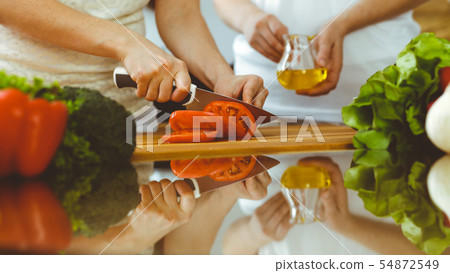 Closeup of human hands cooking in kitchen. Mother and daughter or two female friends cutting Closeup of human hands cooking in kitchen. Mother and daughter or two female friends cutting 54872549