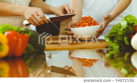 Closeup of human hands cooking in kitchen. Mother and daughter or two female friends cutting Closeup of human hands cooking in kitchen. Mother and daughter or two female friends cutting 54872550