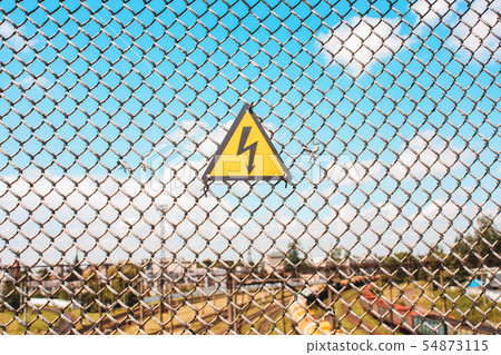 Yellow sign of danger on the fence 54873115