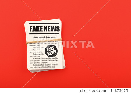 Stack of FAKE NEWS newspapers over red 54873475