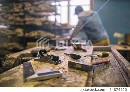 Workshop with tools and blurred carpenter on background Workshop with tools and blurred carpenter on background 54874350