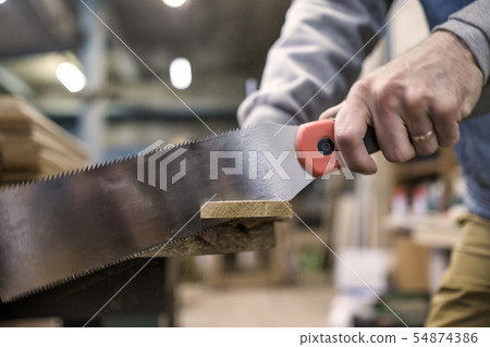 Sawing a wooden board with special japanese hand saw or hacksaw during carpentry 54874386