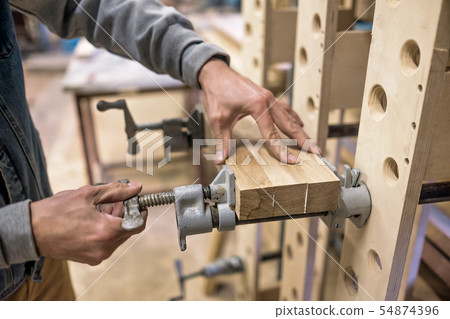 Using clamps and glue to connect wooden timbers for furniture detail Using clamps and glue to connect wooden timbers for furniture detail 54874396