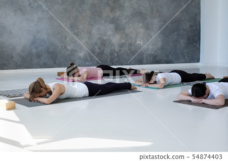 Sporty women practicing yoga lesson in gym relaxing after working out. Sporty women practicing yoga lesson in gym relaxing after working out. 54874403
