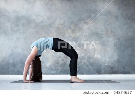 Woman practicing yoga, standing in Urdhva Dhanurasana pose 54874637
