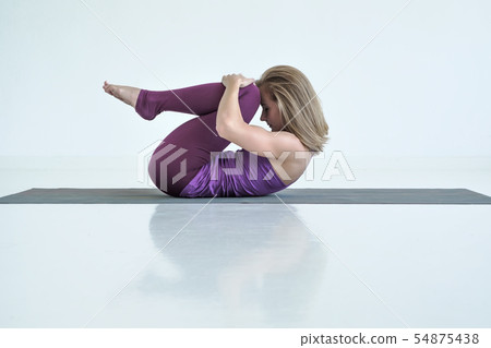 Woman practicing yoga, doing Knees to Chest exercise, Apanasana pose. Woman practicing yoga, doing Knees to Chest exercise, Apanasana pose. 54875438