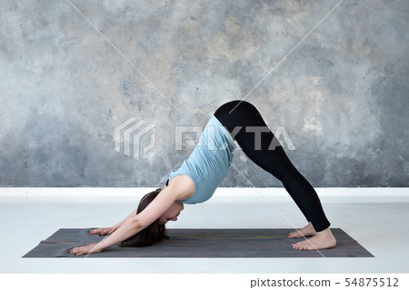 Woman standing in yoga downward facing dog pose, adho mukha svanasana 54875512