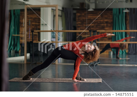 Young woman doing revolved side angle pose, parivrtta parsvakonasana. 54875551