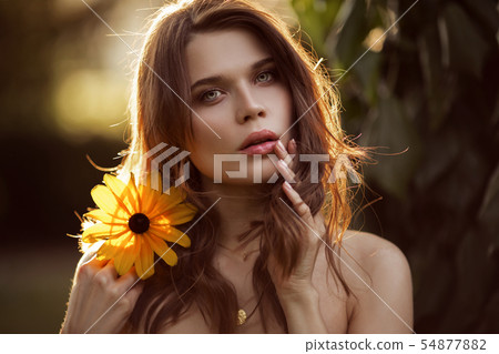 Outdoor fashion photo of beautiful young woman with yellow flower 54877882