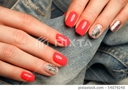 Bright neon red manicure on female hands on the background of jeans. Nail design. Beauty hands. Bright neon red manicure on female hands on the background of jeans. Nail design. Beauty hands. 54879248