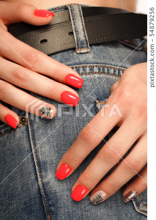 Bright neon red manicure on female hands on the background of jeans. Nail design. Beauty hands. Bright neon red manicure on female hands on the background of jeans. Nail design. Beauty hands. 54879256