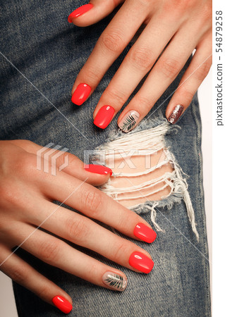 Bright neon red manicure on female hands on the background of jeans. Nail design. Beauty hands. 54879258