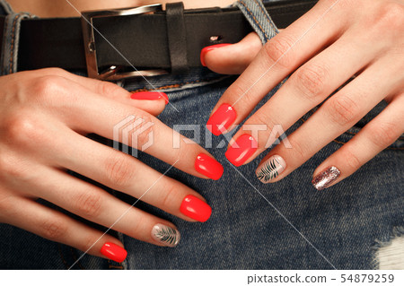 Bright neon red manicure on female hands on the background of jeans. Nail design. Beauty hands. Bright neon red manicure on female hands on the background of jeans. Nail design. Beauty hands. 54879259