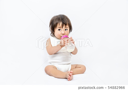 One baby girl sitting on a white background and drinking milk with a baby bottle. Parenting, Parenting, Growth, Developmental Image 54882966