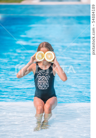 Little girl covering eyes with lemon halves near eyes on background swimming pool Little girl covering eyes with lemon halves near eyes on background swimming pool 54884189