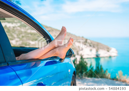 Close up of little girl feet showing from car window background sea Close up of little girl feet showing from car window background sea 54884193