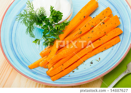 Tasty fried carrot sticks and served with sour cream at plate 54887627