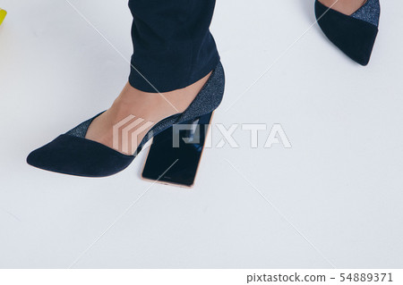 girl puts a foot on the phone. the heel breaks a smartphone. Businesswoman went crazy. Close up on 54889371