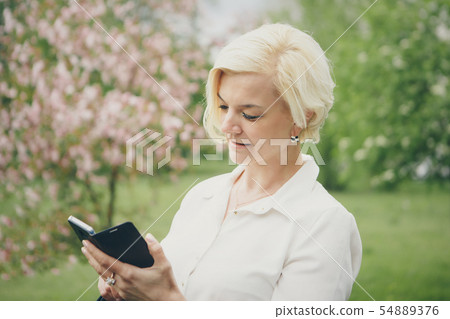 entrepreneur talking on the phone in the Park. Blonde hair Bob works outside. businesswoman with entrepreneur talking on the phone in the Park. Blonde hair Bob works outside. businesswoman with 54889376