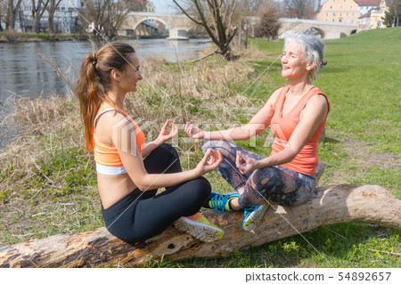 Old and young woman doing yoga on log by the river 54892657