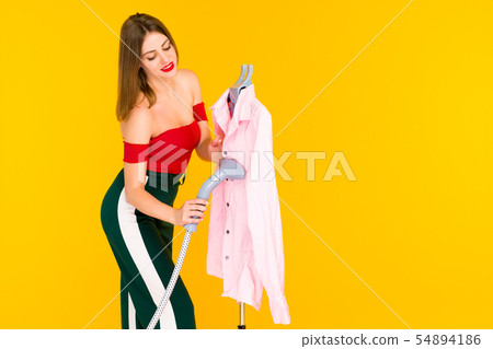Young woman steaming pink shirt at dry-cleaner's Young woman steaming pink shirt at dry-cleaner's 54894186