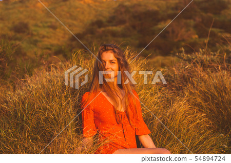 Young smiling blonde girl in red dress sitting Young smiling blonde girl in red dress sitting 54894724