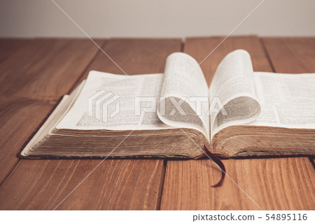 Bible on table with pages folded into heart shape Bible on table with pages folded into heart shape 54895116