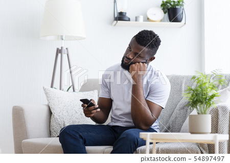 Young man watching tv, using remote control to switch channels 54897497