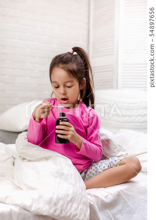 Sick little girl pouring antipyretic syrup for kid 54897656