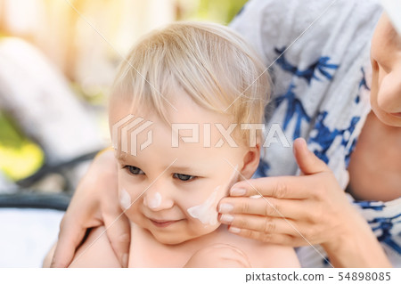 Mother applying sunscreen protection creme on cute little toddler boy face. Mom using sunblocking 54898085