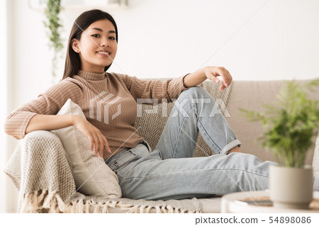 Carefree Teen Girl Looking at Camera, Resting on Sofa Carefree Teen Girl Looking at Camera, Resting on Sofa 54898086