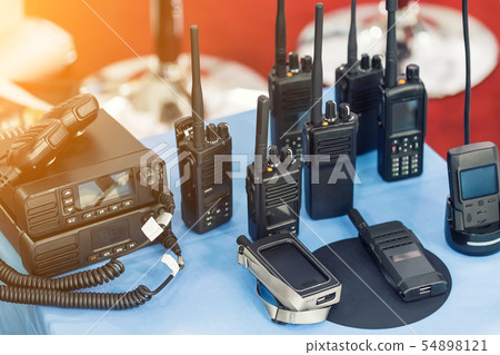 Many portable radio transceivers on table at technology exhibition. Different walkie-talkie radio 54898121