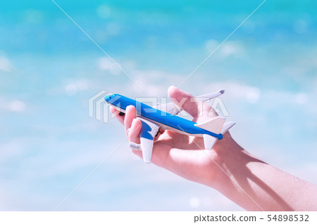 Hand with a toy aircraft against blue water and Hand with a toy aircraft against blue water and 54898532