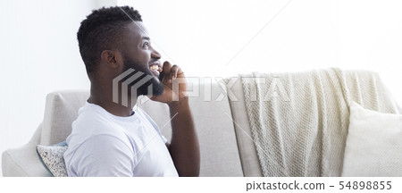 Cheerful african guy enjoying phone talk at home, side view Cheerful african guy enjoying phone talk at home, side view 54898855