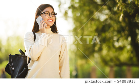 Asian teen girl talking on phone, having break in college 54898915