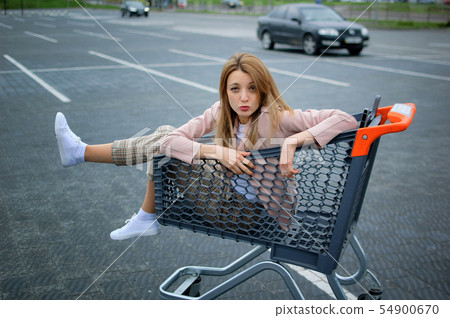 Young attractive girl in the parking lot of the supermarket climbed into the cart. Shopping concept. Young attractive girl in the parking lot of the supermarket climbed into the cart. Shopping concept. 54900670