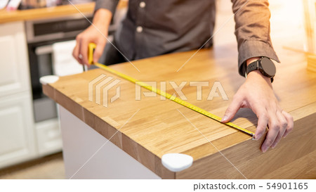 Male hand using tape measure on countertop Male hand using tape measure on countertop 54901165